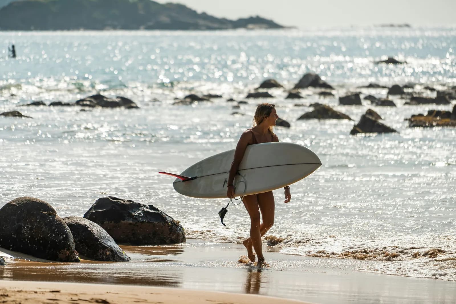 Surfer carrying a board along the beach at Arugam Bay on Sri Lanka's east coast