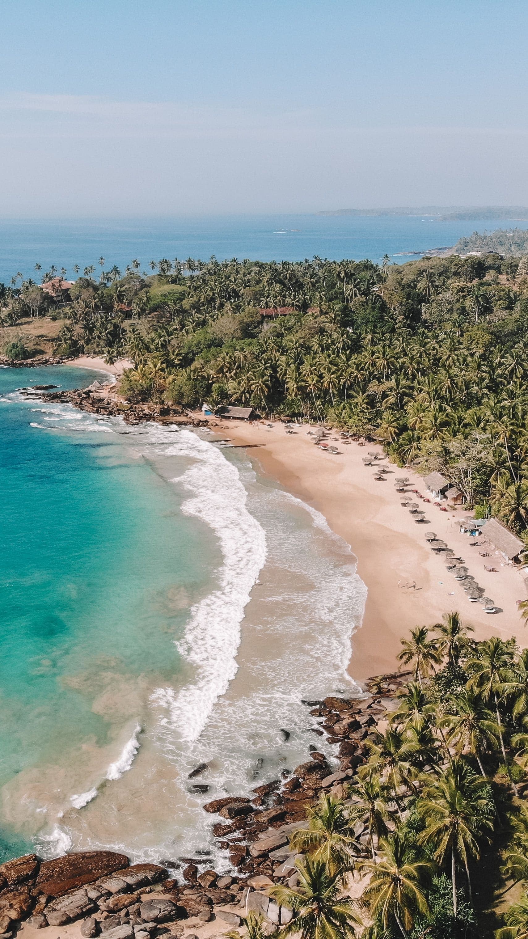 Sunlit sandy beach with crystal clear turquoise waves rolling in Sri Lanka.