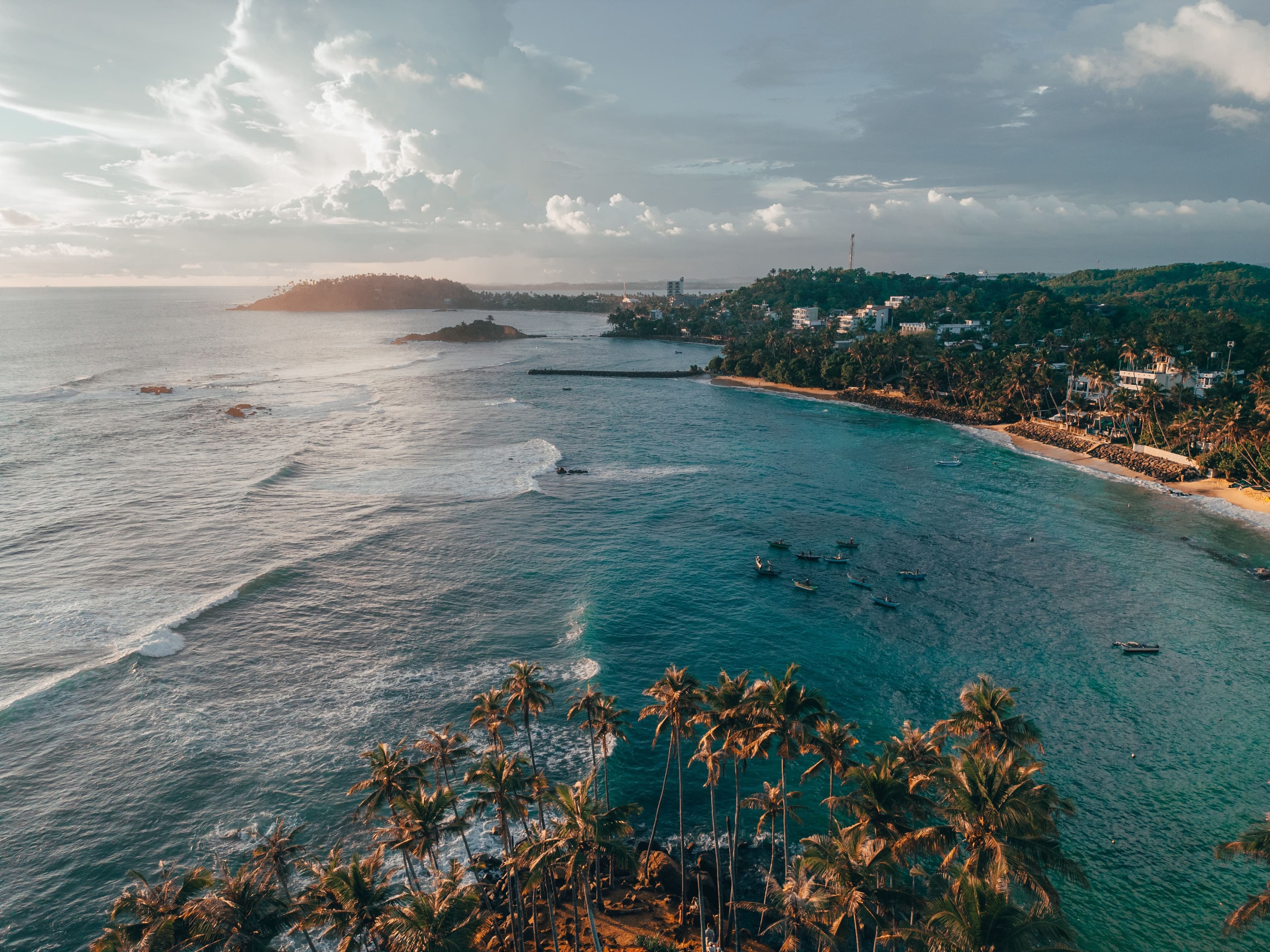 Panoramic sandy coastline stretching into the horizon with foamy breakers.