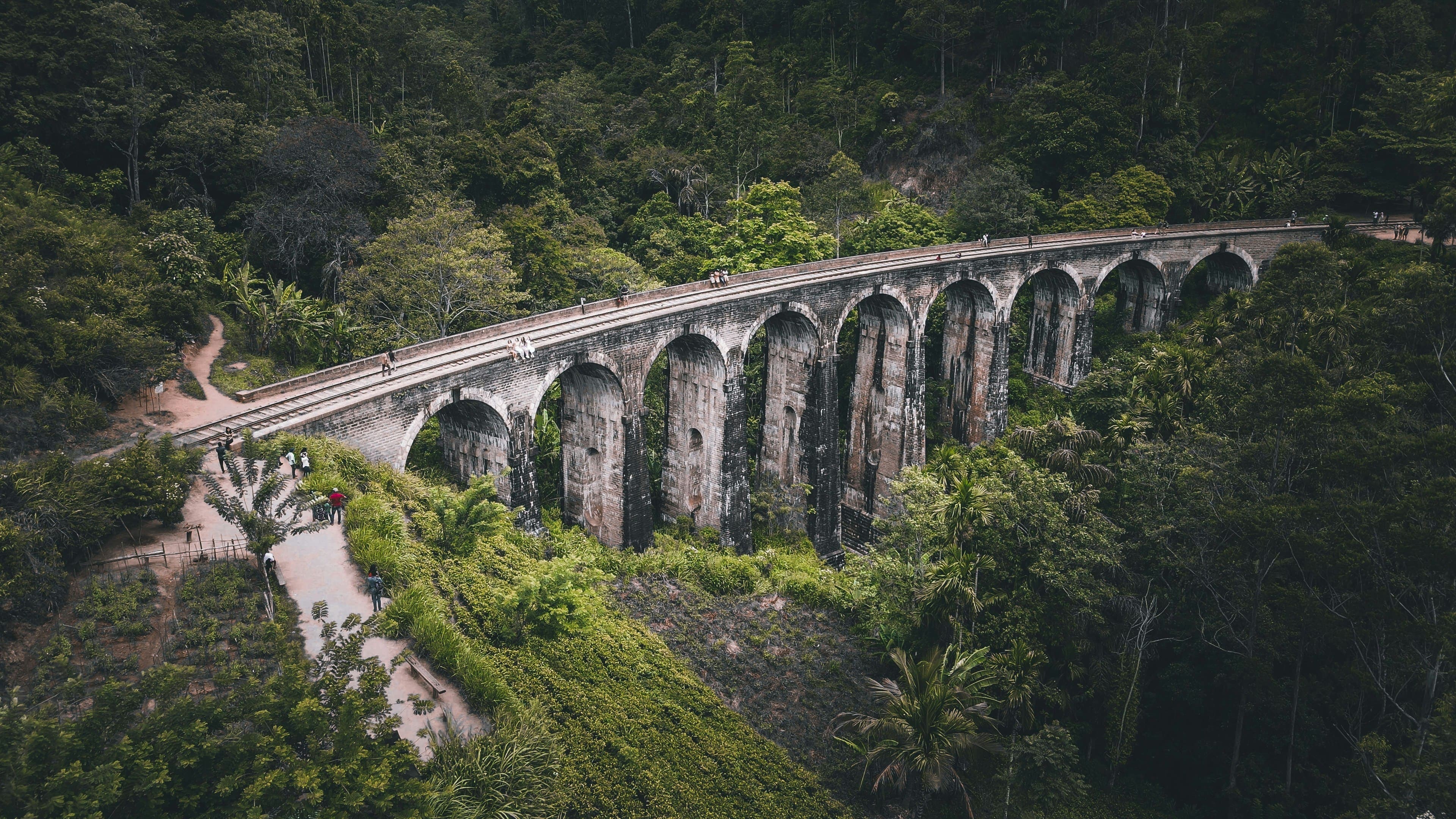 Historic colonial Nine Arches Bridge railway viaduct curving through lush tea hills in Ella.