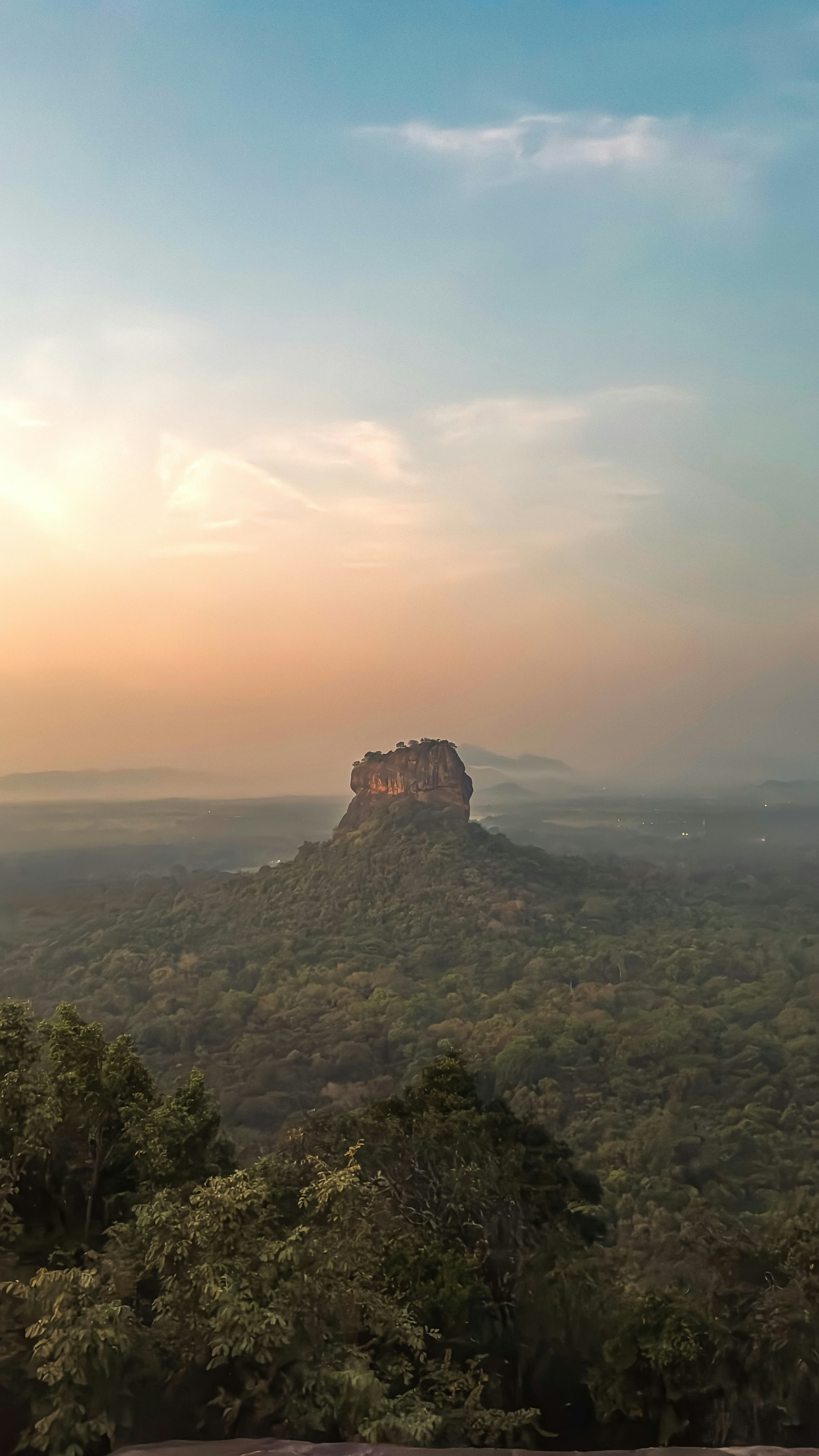 Iconic steep granite monolith of Sigiriya rising dramatically above the jungle canopy.