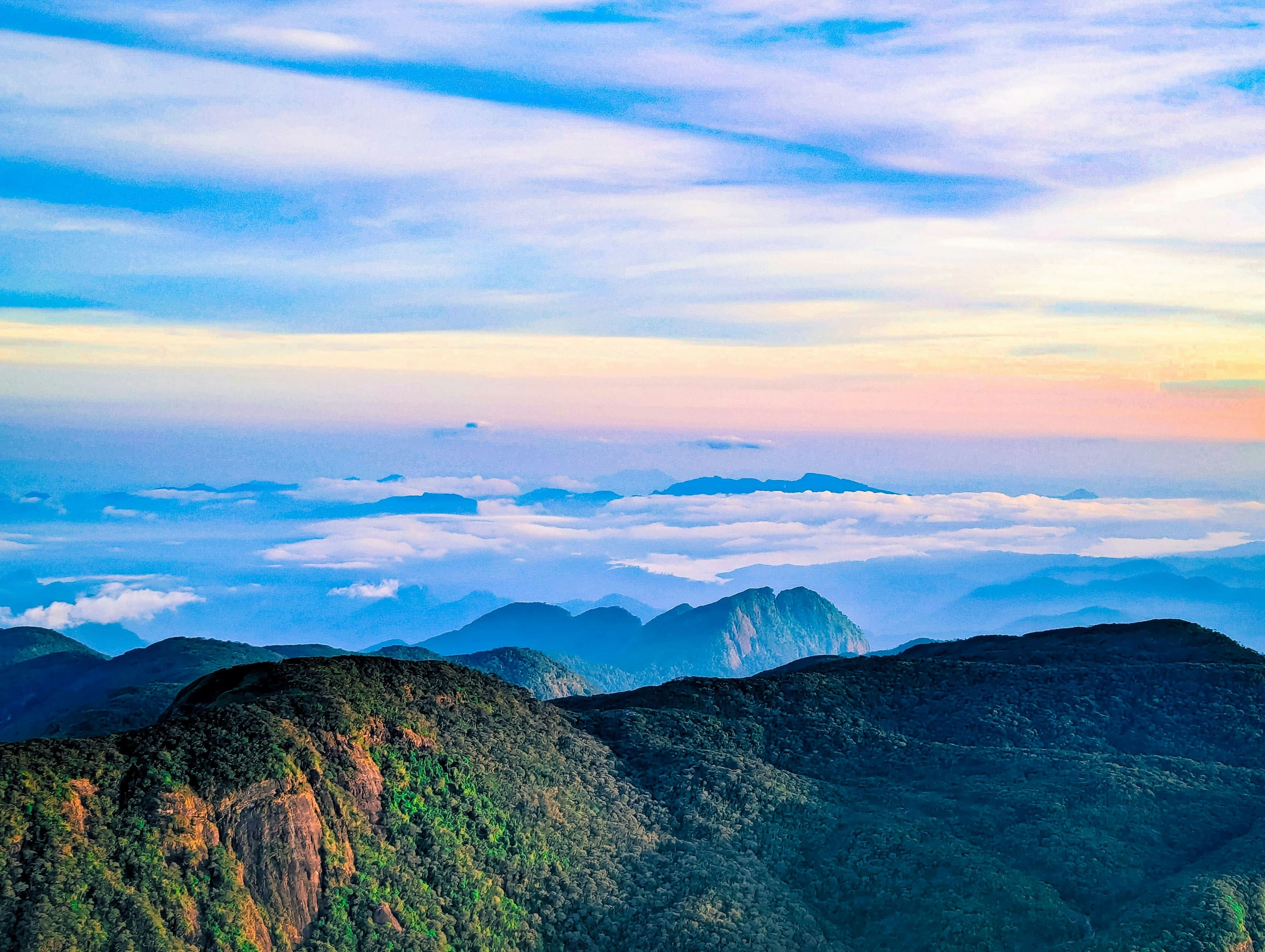 Sacred mountain summit of Sri Pada glowing in golden dawn light above cloud sea.