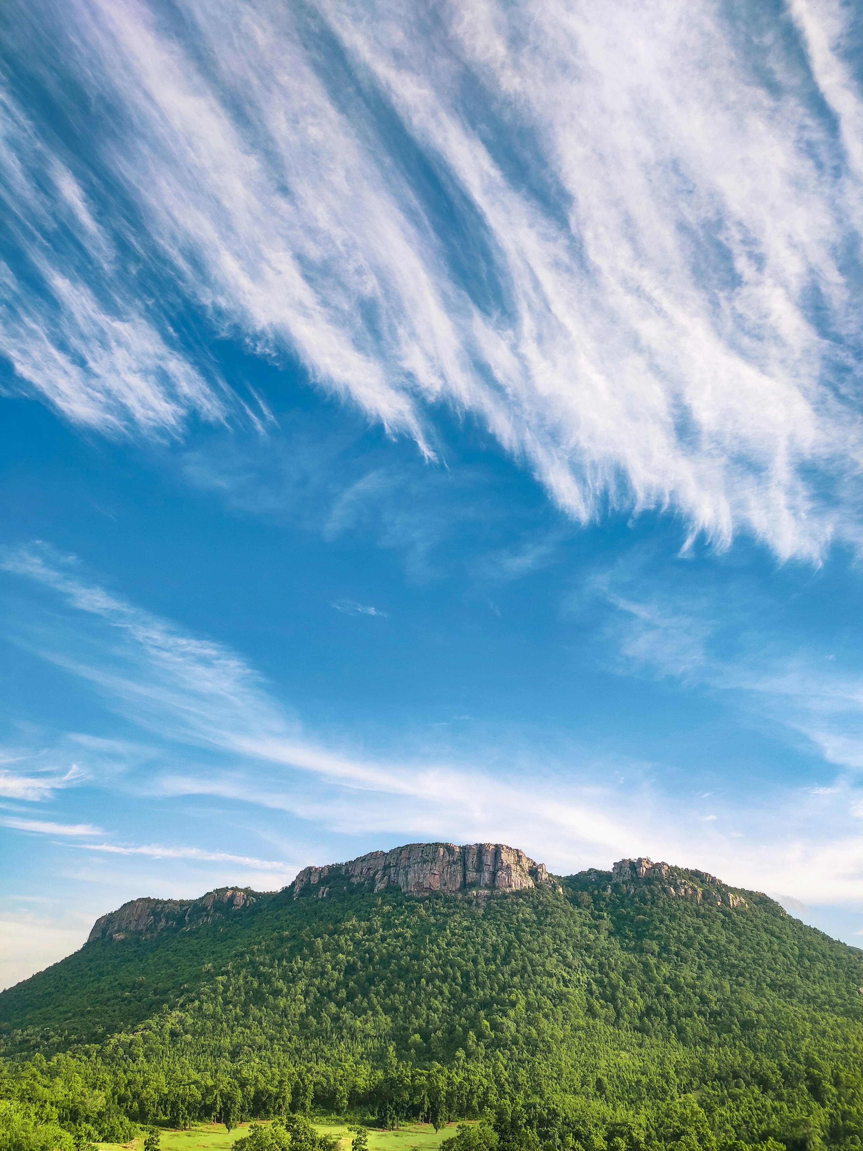 Puffy white clouds floating over verdant green mountain peaks.